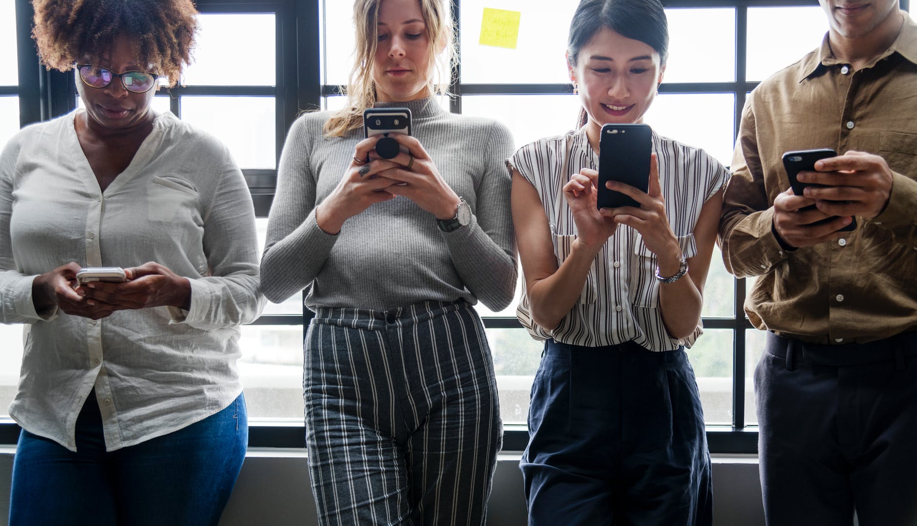 three women standing near man holding smartphones